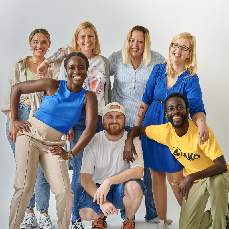 Ein Gruppenbild mit sieben jungen Menschen vor einer weißen Wand