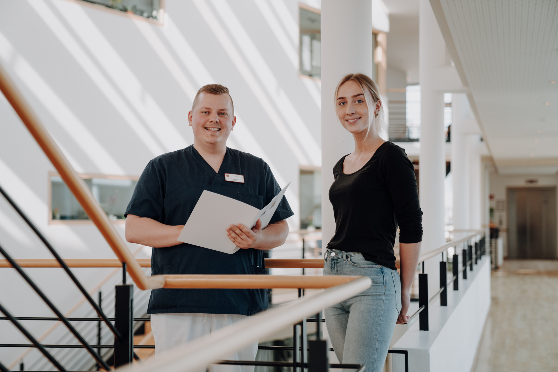 Ein junger mann mit einer Mappe in der Hand, der neben einer jungen Frau in einem großen Foyer steht