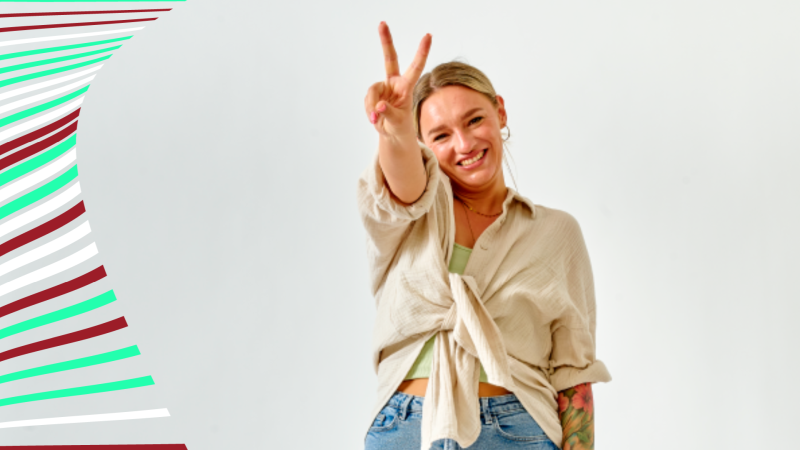 Eine Frau zeigt das Peace-Zeichen und lacht in die Kamera