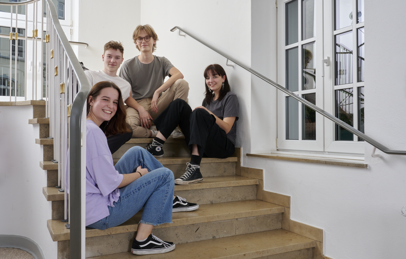 4 Personen sitzen auf einer Treppe